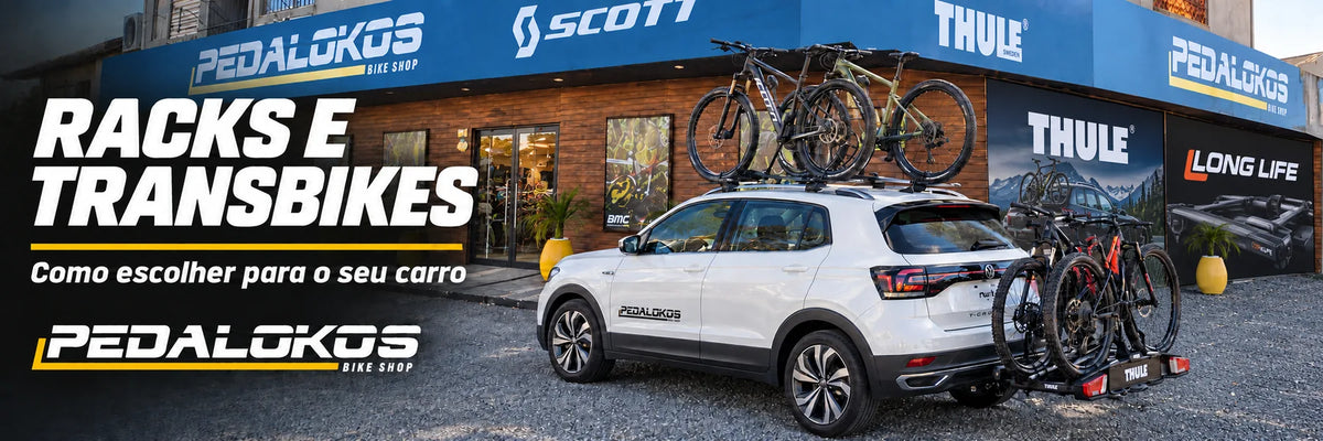 Carro com rack e transbike de engate na fachada Pedalokos, com painéis Thule e Long Life e piso de pedras.